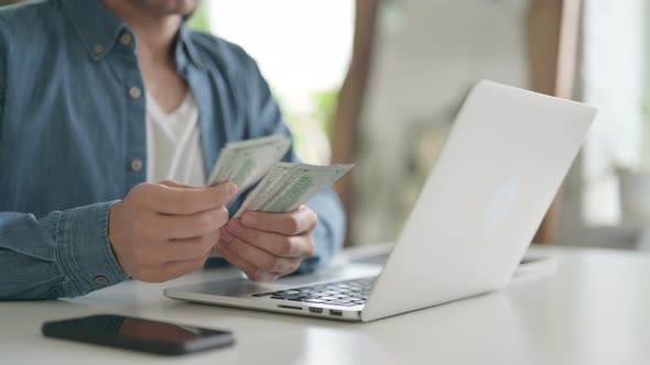 Close Up of Man Counting Dollars While Working on Laptop