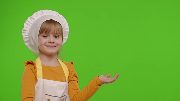Child Girl Dressed Cook Chef in Apron Pointing at Right on Blank Space on Chroma Key Background