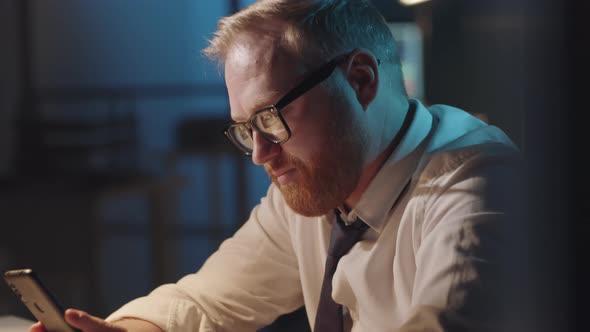 Businessman Typing on Smartphone Late in Office