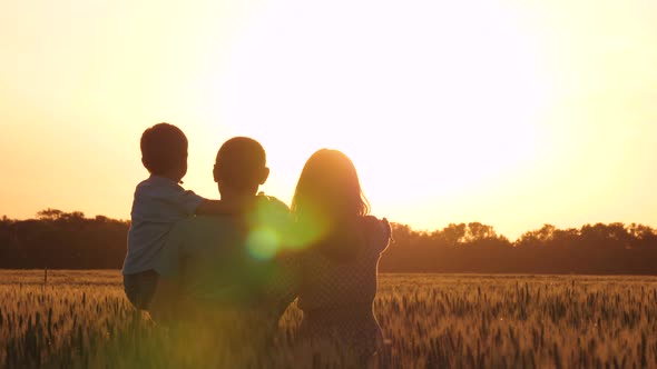 Happy Family on the Background of a Beautiful Sunset. A Father Holds a Small Child in His Arms. A