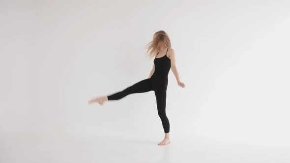 An Energetic Young Girl in Tight Black Clothes Makes a Swing Leg and Takes a Vertical Split