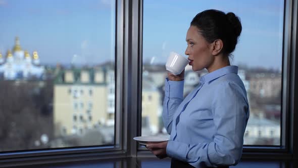 Confident Businesswoman Drinking Coffee By Window