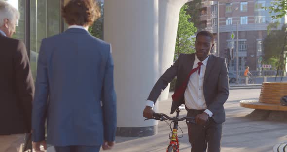 Afroamerican Businessman Pushing Bicycle Walking Outdoors Downtown