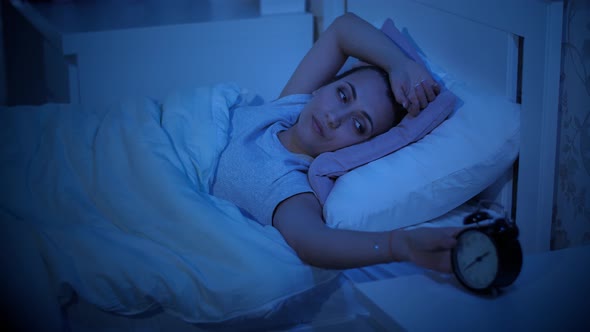 Woman with Insomnia Looks at the Alarm Clock