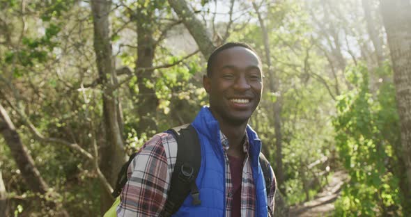 Portrait of smiling african american man in forest during hiking in countryside