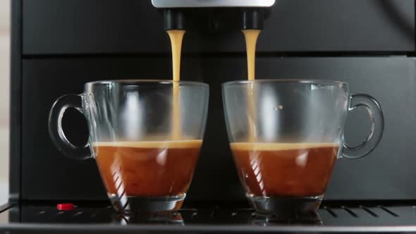 Brewed Coffee Is Poured From the Coffee Machine Into Glass Cups