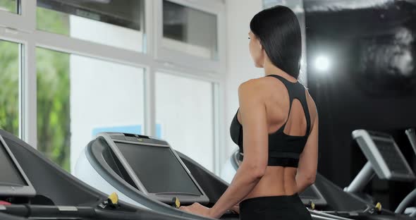 Athlete Woman Using Run Machine in Fitness Center