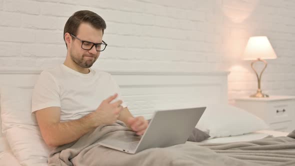 Young Man with Laptop Having Wrist Pain in Bed