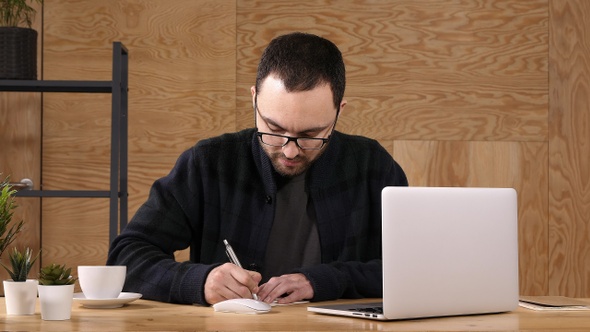 Hipster Taking Notes Down from His New Laptop Computer