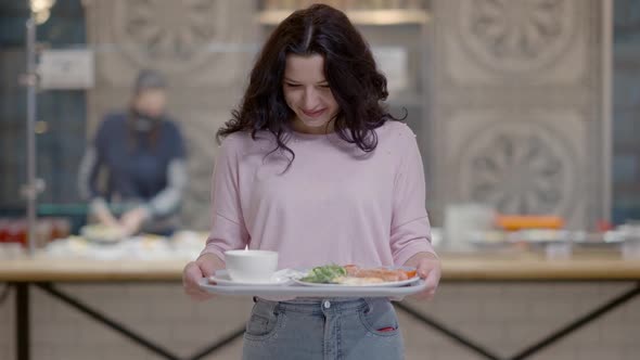 Middle Shot of Happy Brunette Curlyhaired Young Caucasian Woman Posing with Food Tray in Selfservice