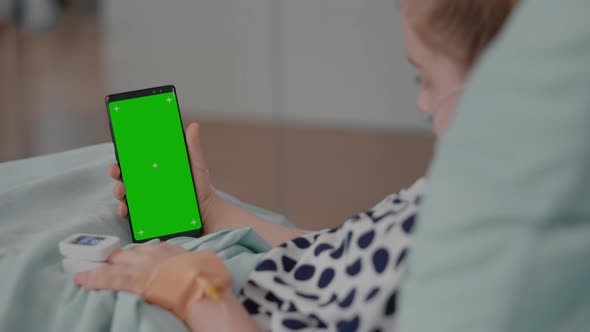 Sick Girl Resting in Bed with Medical Oximeter on Finger Looking at Green Screen Mock Up Chroma Key