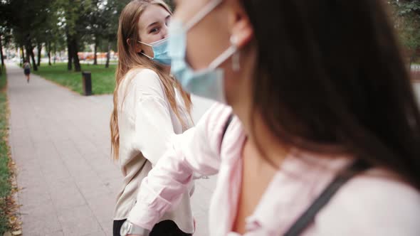 Students in protective medical mask greet each other elbows during pandemic of coronavirus.