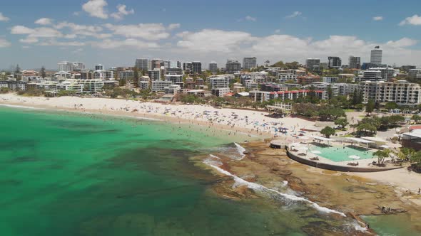 Aerial drone footage of ocean waves on a busy Kings beach, Caloundra, Australia