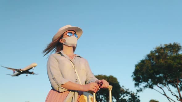 Slow Motion Woman in Face Mask Looking at Sunset, Landing Airplane on Background