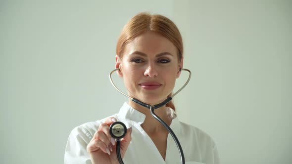 Close-up of Woman Doctor in White Coat in Clinic at Workplace Holds Stethoscope in His Hand and