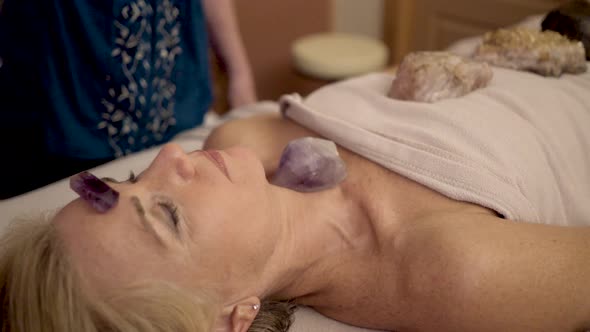 Very tight shot of therapist using a crystal pendulum over a patient’s head for mystical healing.