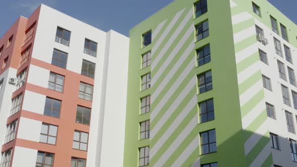 Tilt Up View of Exterior of Modern Apartment Buildings with Colorful Walls Located at Edge of City