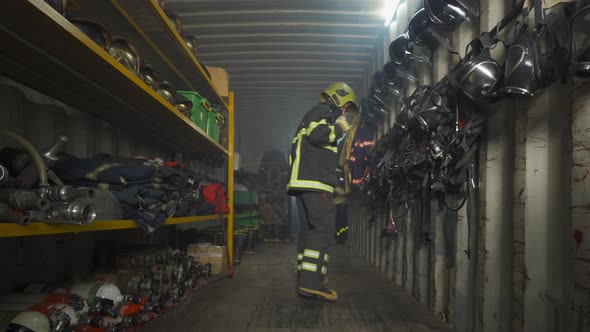 A caucasian firefighter or fireman with uniform inspecting in protection gear storage