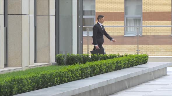 Successful Attractive Businessman Leaves the Building and Goes Along It. Slow Motion