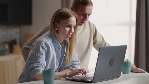 Bonding Millennial Smiling Couple Looking at Laptop Screen Choosing Goods in Online Store Involved