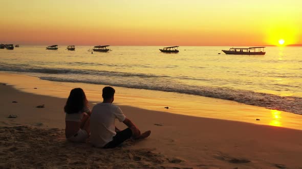 Young couple in love on marine shore beach voyage by blue ocean with white sand background of Indone