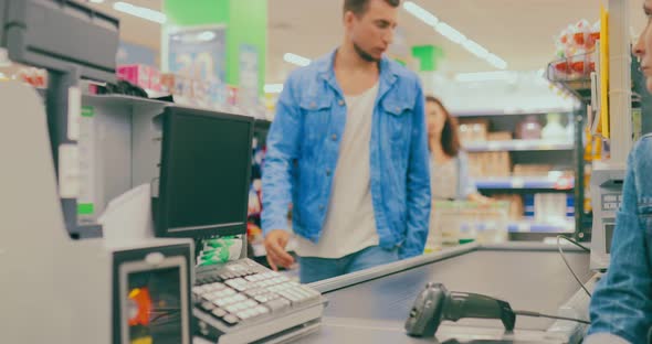 Young Woman Walks Up to the Checkout Counter and Spreads the Goods