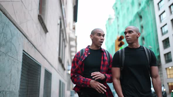 Two handsome bald African brothers talking and walking on the street