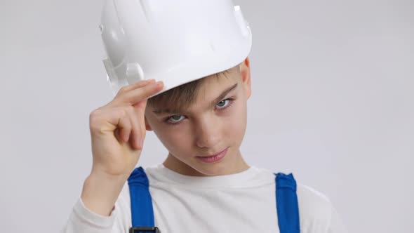 Headshot Portrait of Confident Little Foreman Saluting Touching Hard Hat Looking at Camera