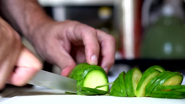 Close shot of a zucchini being chopped on a white table