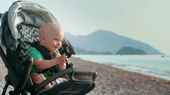 Happy Baby Clapping Hands in Stroller at Sea Beach. Little Boy Clapping Hands