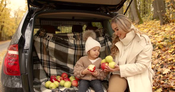 Baby Girl with Mom in the Trunk of a Car in the Autumn Park