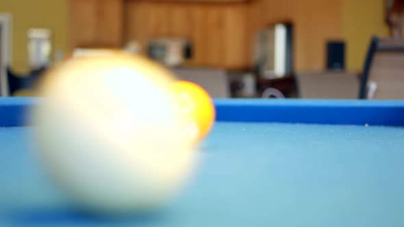 Pool balls rolling around on billiards table.