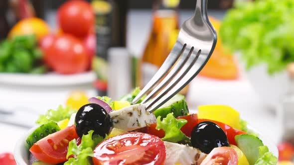 Greek salad on fork, fresh vegetable salad served with healthy food ingredients