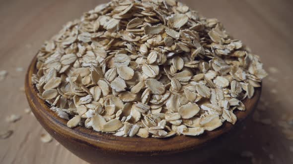 Slow motion of oatmeal falling into an earthen bowl. Whole grain cereals