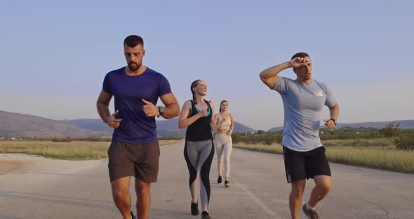 Multiethnic Group of Athletes Running Together on a Panoramic Countryside Road