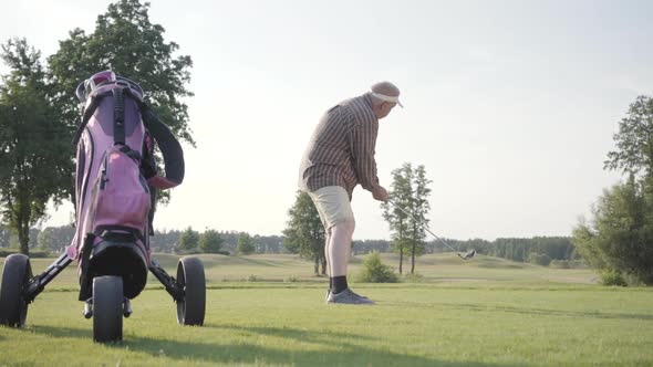 Mature Man Playing Golf on the Golf Field. Senior Man Hit the Ball Using Golf Club. Old Gentleman