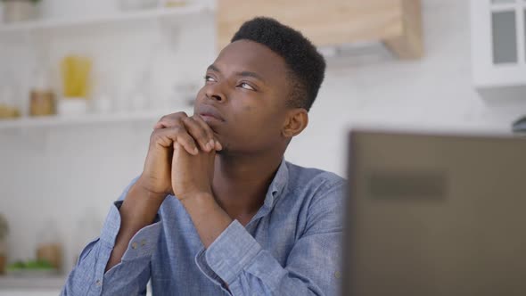 Handsome Young Man Looking Away Thinking Sitting in Home Office Indoors with Laptop