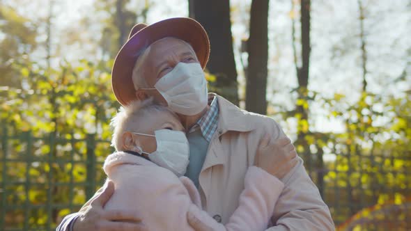 Portrait of Senior Couple Wearing Protective Mask Embracing in Autumn Park