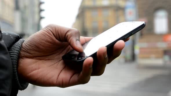 Black Man Works on Smartphone - Urban Street with Cars - City - Closeup