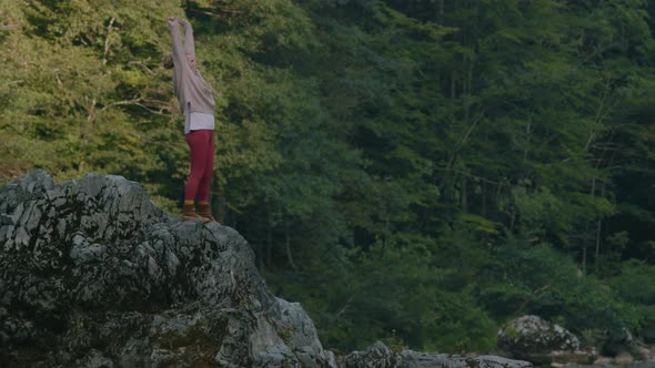 Closeup of travel woman with dreadlocks and backpack on top of mountain