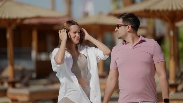 a Woman with Long Hair in a White Shirt and a Man in a Pink Tshirt are Smiling Talking and Walking