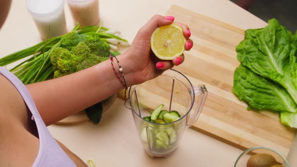 Woman Squeezing Lemon Juice with Hands Into Blender Closeup Cooking Green Detox Smoothie in the