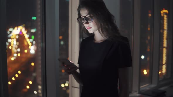 Portrait of a Young Girl in the Light of the Smartphone Screen. Girl Uses a Mobile Phone Against the