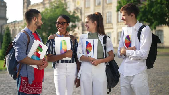 Four Smiling Confident Multiethnic Students Standing with Paperwork Outdoors at University Campus