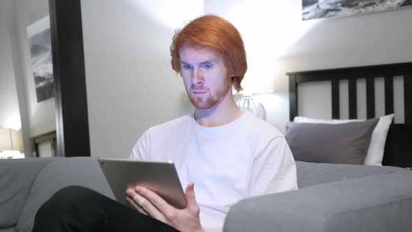 Reaction to Success By Man Using Tablet in Bedroom