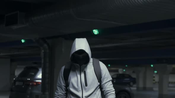 Man Criminal in the Balaclava and Hood Looking at the Camera in Underground Parkingslow Mo