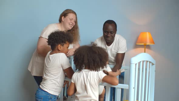Happy Mixed Race Family Standing Near Crib with Infant Baby in Nursery