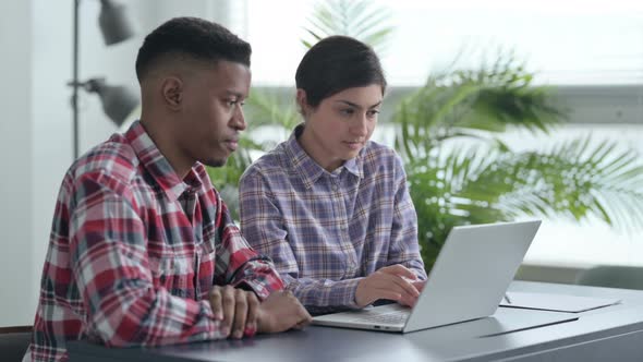 African Man and Indian Woman Celebrating Success on Laptop