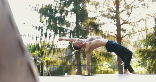 Sportsman Performing Yoga Pose Balancing on One Hand in Nature