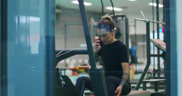 Woman Talking To Cellphone at Gym. Woman Exercising with Rowing Machine at gym.Front View, Slow